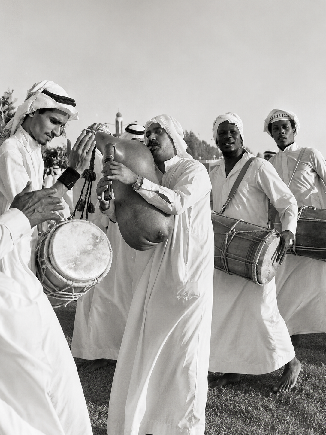 Gulf musicians in traditional clothing performing with drums and a folk wind instrument